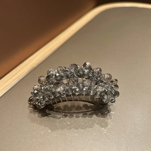 Detailed view of curved banana clip with sparkling grey crystals and beaded resin base