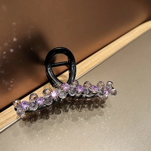 Close-up of elegant hair claw clip with multicolored crystals on a black base