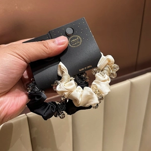 Detail of black and champagne satin scrunchies with crystal beads on a handmade display card