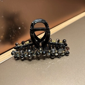 Detail of elegant black hair claw clip featuring grey crystal beads and gold metal claws