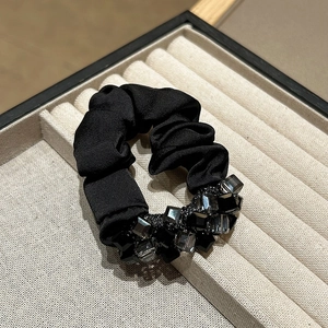 Detail of black satin scrunchie with sparkling grey crystal beads on a jewelry tray