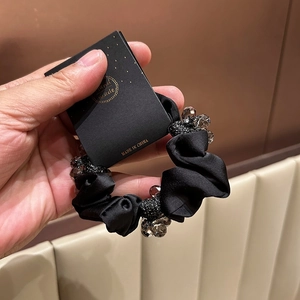 Detail of black satin scrunchie with grey crystal beads and handmade packaging