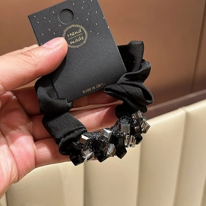 Detail of black fabric hair scrunchie with sparkling gray square crystal beads