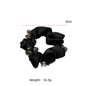 Detail of 8cm black satin scrunchie featuring crystal beads and pleated fabric texture