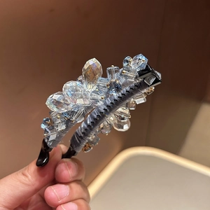 Détail d'une pince banane en soie grise ornée de cristaux bleus multifacettes