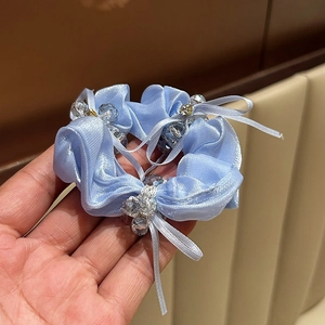 Detailaufnahme eines hellblauen Satin-Haargummis mit Schleife und Kristallperlen