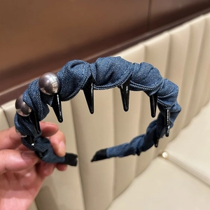 Detail of blue denim headband featuring decorative grey pearls and black metal spikes
