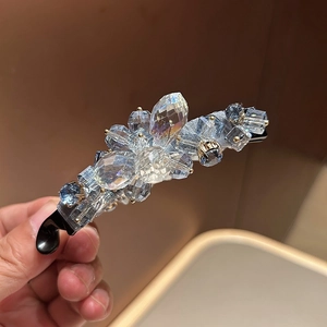 Détail macro de cristaux bleu ciel et clairs sur une pince à cheveux noire rétro