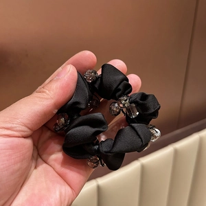 Detailed shot of black satin scrunchie decorated with sparkling crystal beads