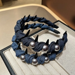 Detail of denim headbands with black punk spikes and silver pearls on display tray