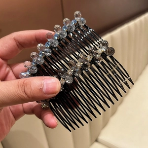 Detail of crystal hair comb with blue and grey beads held in hand for a close-up view