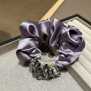 Elegant purple satin silk scrunchie with crystal bead accents on a jewelry tray