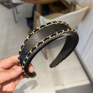 Détail d'un serre-tête noir vintage avec double chaîne en métal doré et cuir tressé