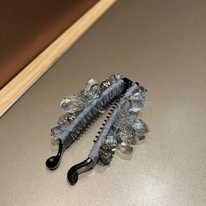 Gros plan sur les perles de cristal bleu-gris d'une élégante pince à cheveux banane