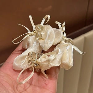 Detail von champagnerfarbenen Satin-Scrunchies mit Kristallperlen und Schleifen