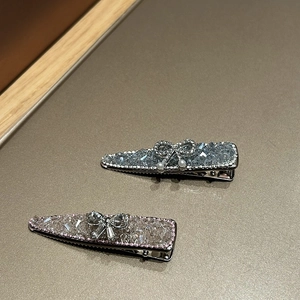 Detail of blue and pink crystal bow hair clips with pearls on a textured background