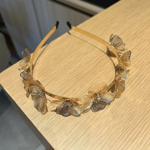 Close-up of golden metal headband with hollow floral petals and sparkling crystal centers
