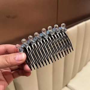 Detail of a curved hair comb with sparkling blue and clear crystals on a black resin base