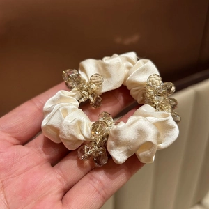 Elegant champagne silk scrunchie featuring faceted crystal beads for a minimalist hair look