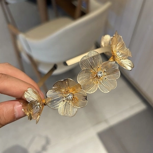 Detailed macro of golden metal flower headband with intricate petals and crystal centers
