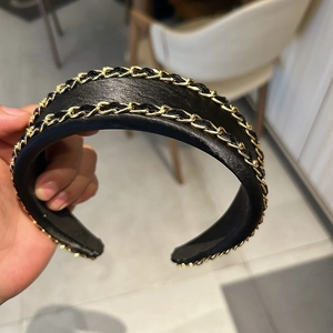 Vue détaillée du serre-tête en cuir noir avec doubles chaînes dorées entrelacées