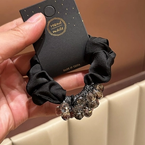 Detailed macro view of black satin scrunchie with sparkling crystal beads decoration