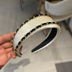 Détail d'un serre-tête rembourré en velours crème avec double chaîne dorée élégante