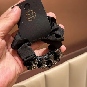 Detail of black silk scrunchie with sparkling square crystal beads and paper card