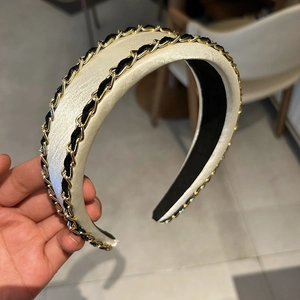 Détail du serre-tête en satin crème avec double chaîne dorée et ruban noir tressé