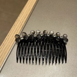 Detail view of a 12-tooth black hair comb with sparkling grey and clear crystal beads