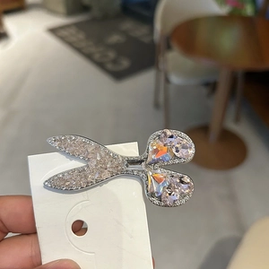 Elegant silver scissor hair clip with pink rhinestones and crystals on a white card