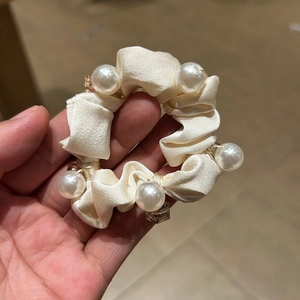 Detailed view of elegant cream satin scrunchie featuring large pearls and crystal beads