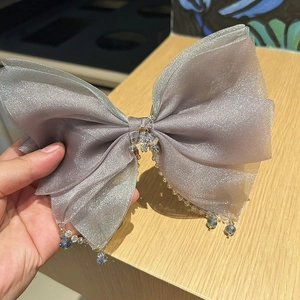 Detailed view of mauve tulle bow hair clip with crystal beads and teardrop pendant