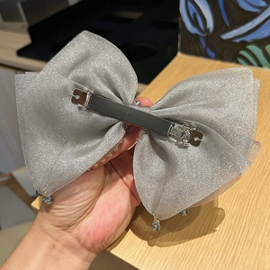 Detail of silver silk bow hair clip featuring dangling crystal beads and spring metal fastener