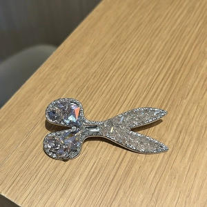 Detailed macro shot of silver scissors hair clip with sparkling blue rhinestones