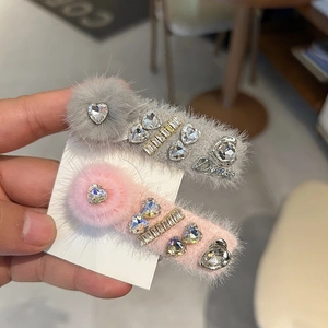 Vue détaillée des barrettes en fausse fourrure grise et rose avec cristaux brillants