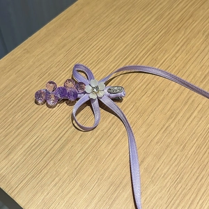 Détail de la barrette à nœud violet avec des perles en cristal sur fond de bois