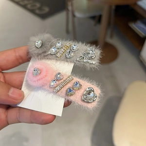 Détail de barrettes à cheveux en peluche avec strass brillants en rose et gris clair