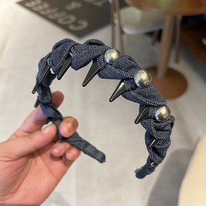 Détail d'un serre-tête en denim avec pointes noires et perles argentées