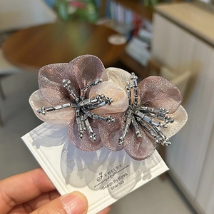 Elegant purple organza flower hair clip with crystal beads on a white display card