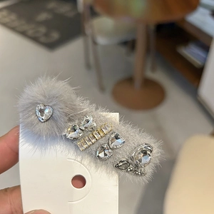 Détail de la pince à cheveux en fausse fourrure grise avec strass brillants et breloque Dance
