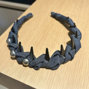 Détail d'un serre-tête en denim bleu avec pointes punk noires et clous en métal argenté