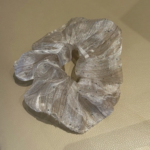 Macro shot of champagne gold seersucker scrunchie with sparkly rhinestones and pleated texture