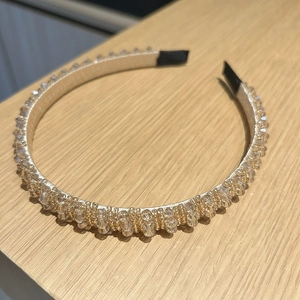 Vue détaillée du serre-tête avec perles de cristal champagne sur fond en bois clair