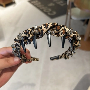 Detailed macro view of handmade leopard print headband with black spikes and crystals