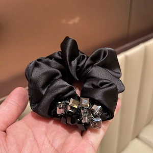 Detailed macro view of black satin scrunchie with faceted crystal decorations