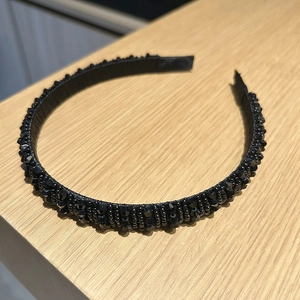 Détail de perles de cristal noir artisanales sur un serre-tête large pour femme