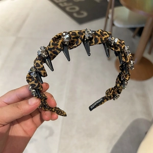 Detail showing leopard print headband with black spikes, rhinestones, and handmade label