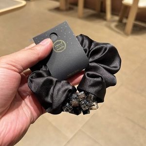 Detail of handmade black satin hair scrunchie with vintage crystal beads on display card
