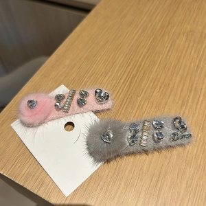 Vue détaillée des pinces à cheveux en peluche rose et grise avec accents en strass